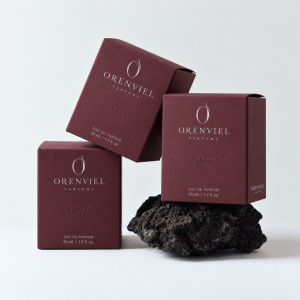 Three grape-purple specialty paper perfume folding cartons with ORENVIEL silver foil branding and blind embossing