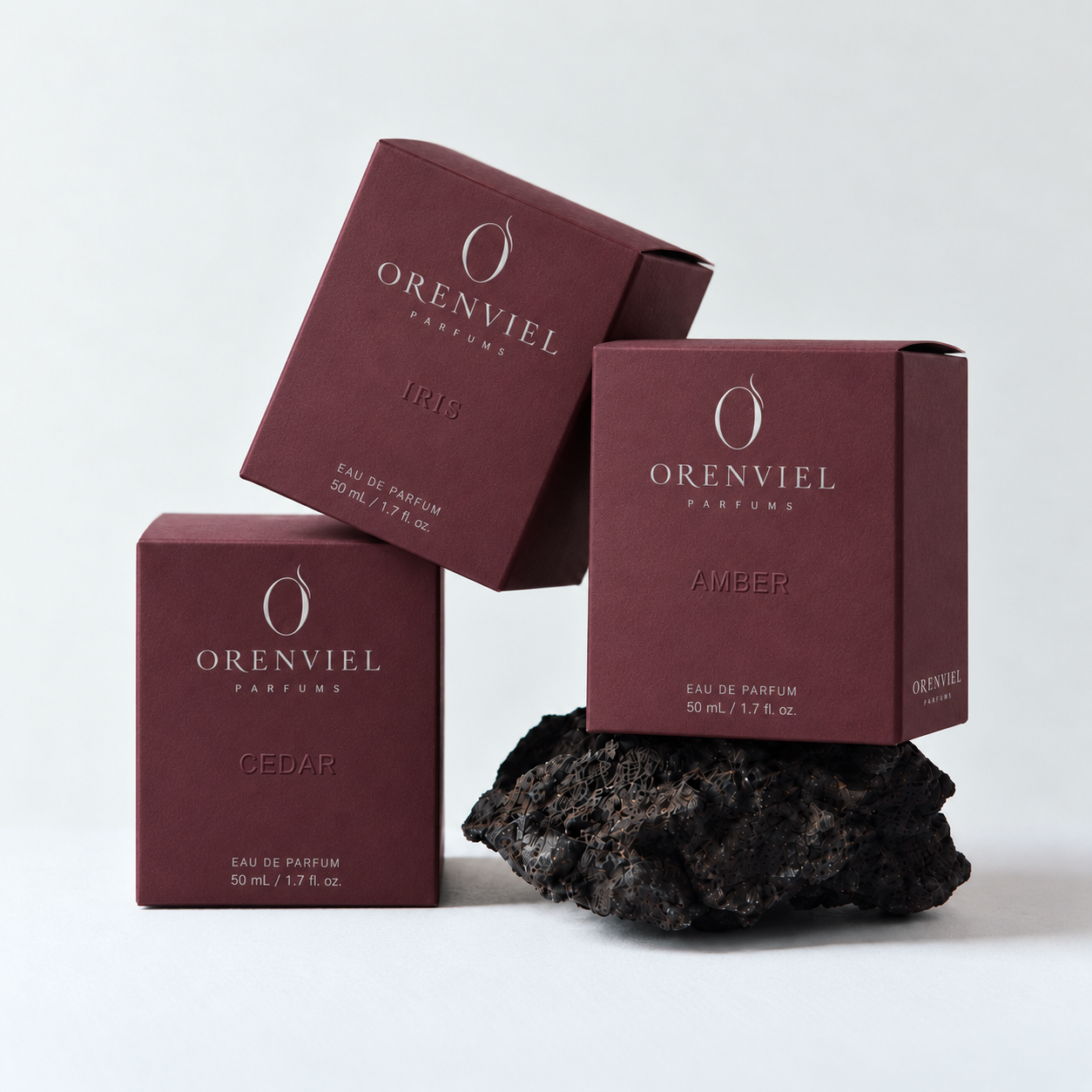 Three grape-purple specialty paper perfume folding cartons with ORENVIEL silver foil branding and blind embossing