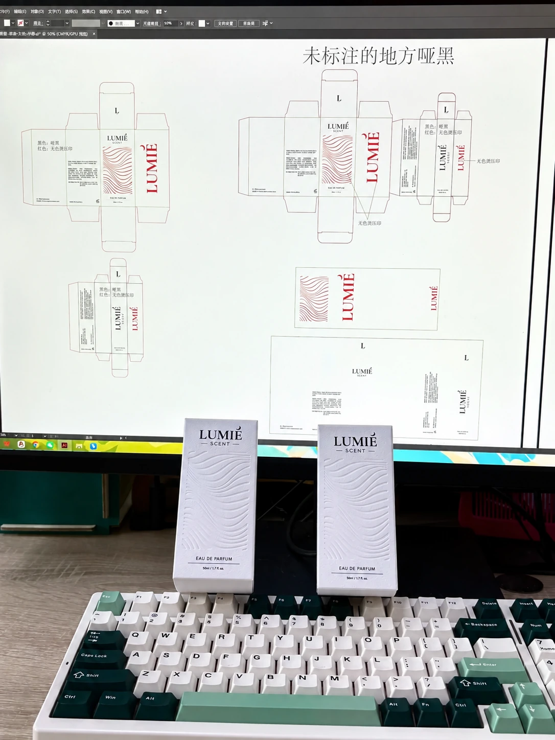 Perfume cartons in front of their dieline artwork on a monitor