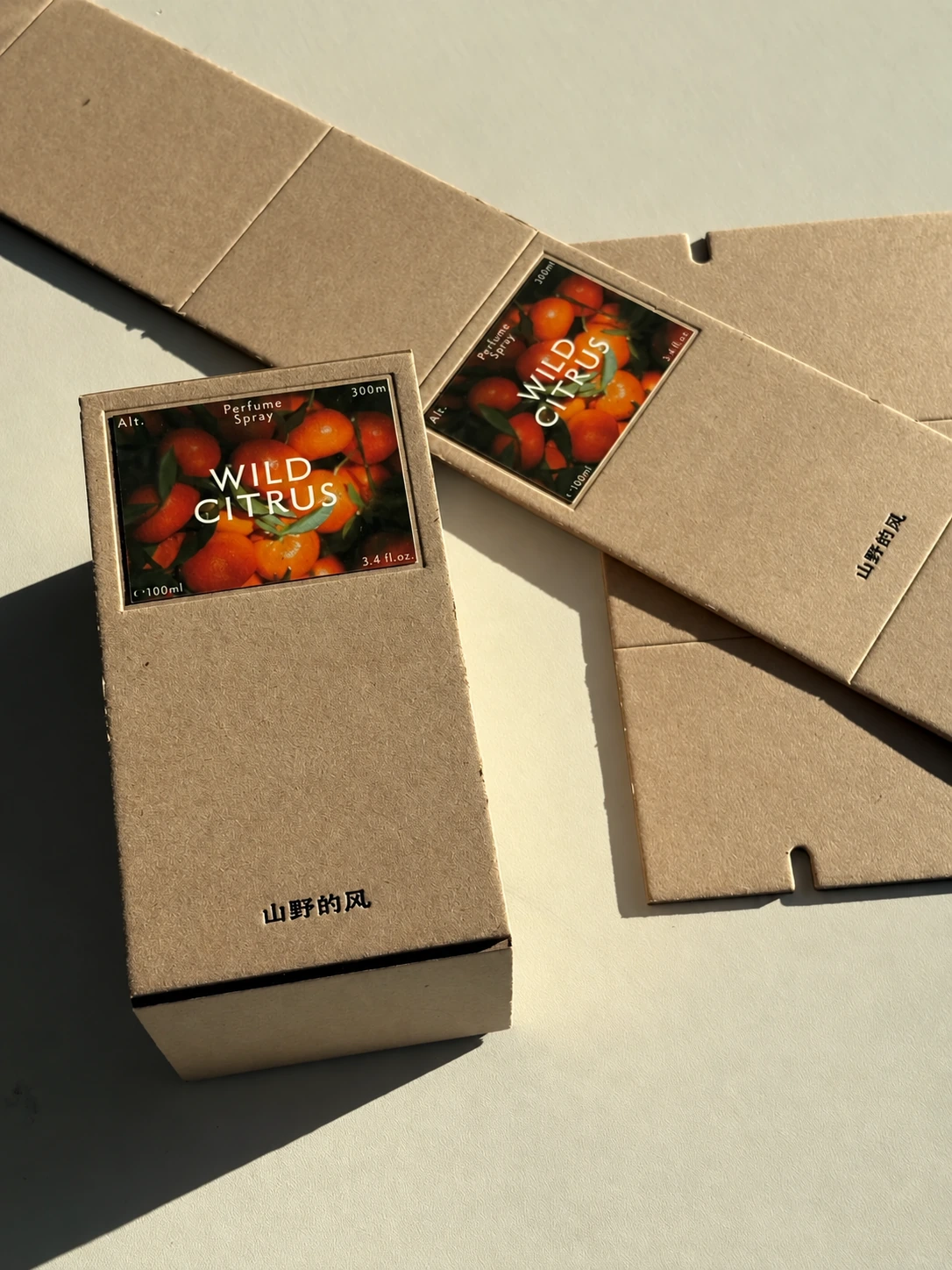 Brown paperboard perfume packaging shown flat and assembled