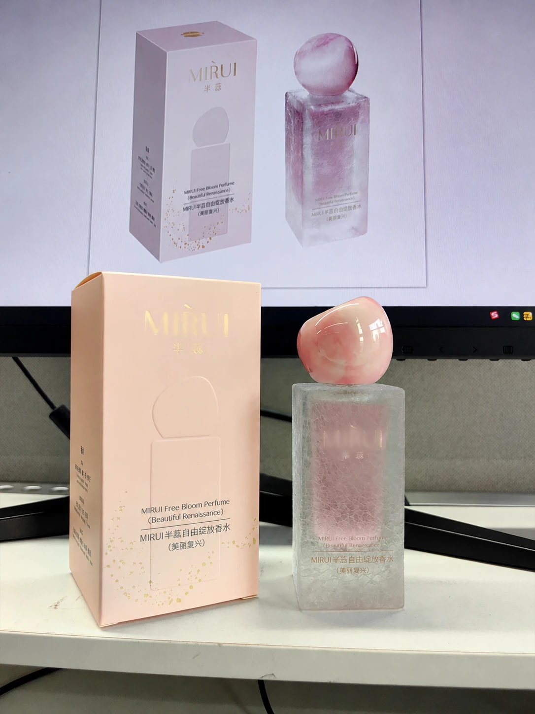 Pink perfume bottle and matching carton beside a screen reference