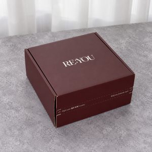 Closed burgundy folding mailer box with white logo and front tear-strip opening