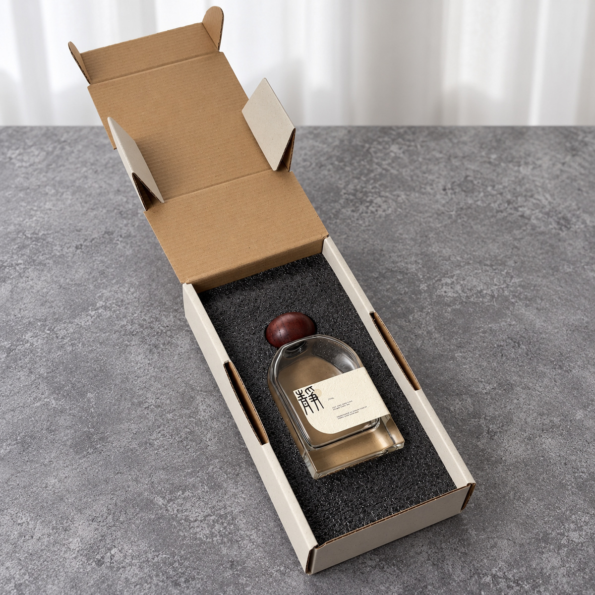 Open cream long perfume mailer box with a bottle fitted into a black foam insert
