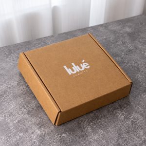 Closed low-profile kraft brown folding mailer box with white logo printing