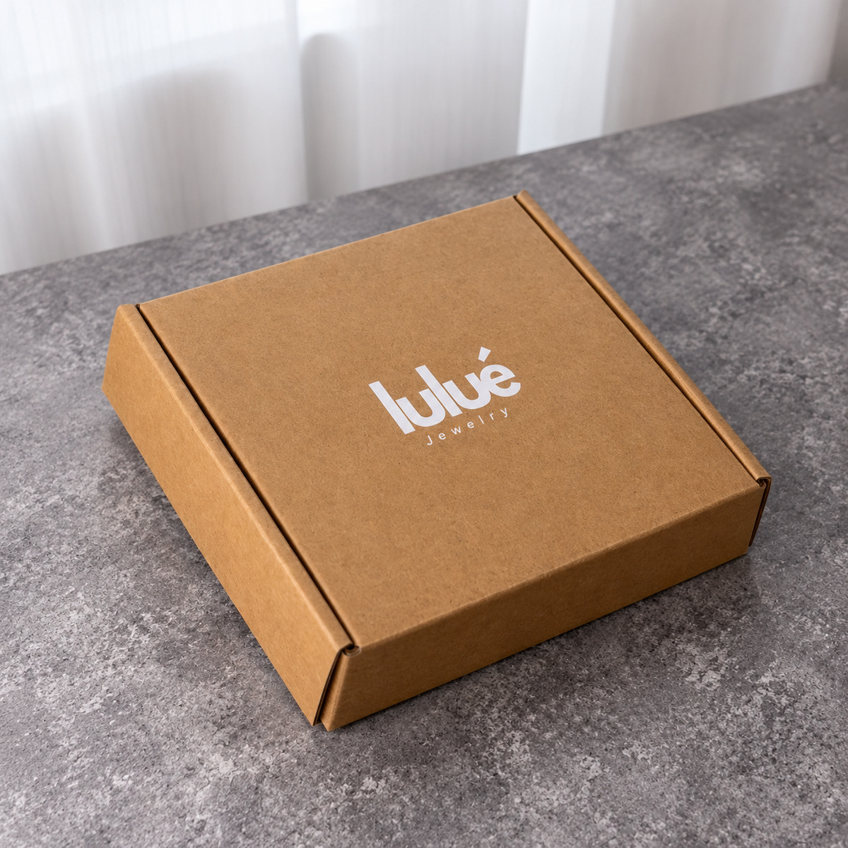 Closed low-profile kraft brown folding mailer box with white logo printing