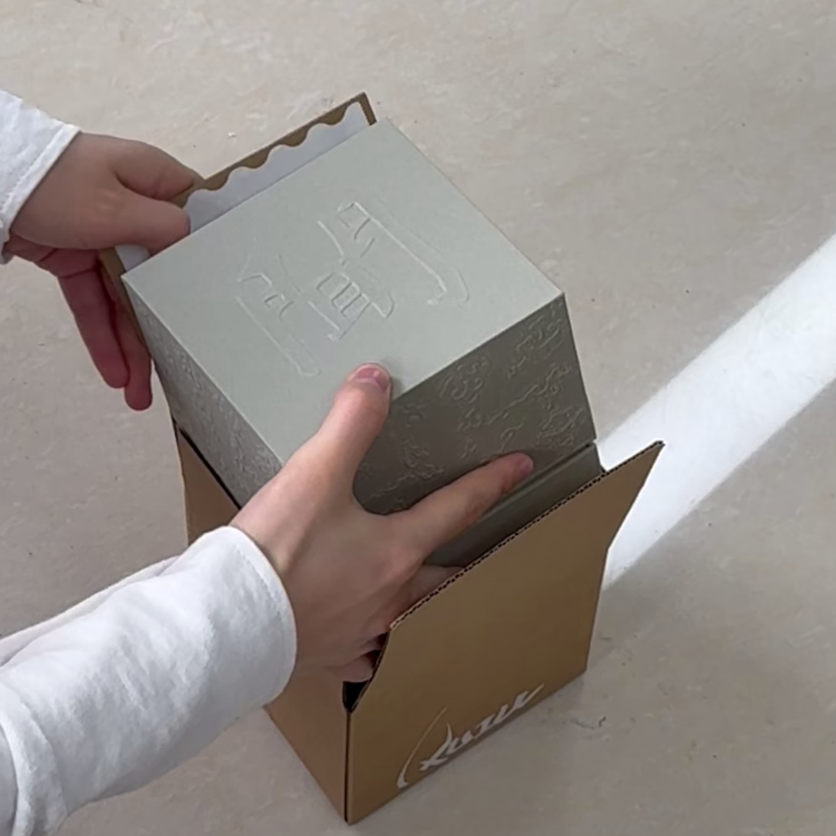 Open kraft shipping carton showing the inner base and flaps before placing a gift box