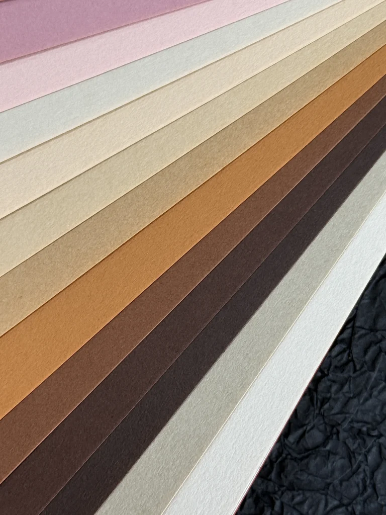Overlapping neutral, cream and brown paper samples showing surface texture