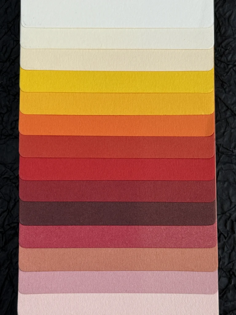 Overlapping warm-toned paper samples showing their surface texture