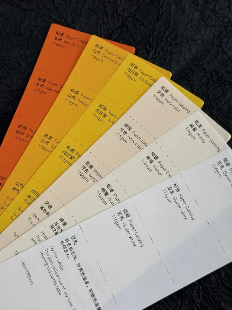 Yellow, orange, ivory and off-white paper cards with color names and weights