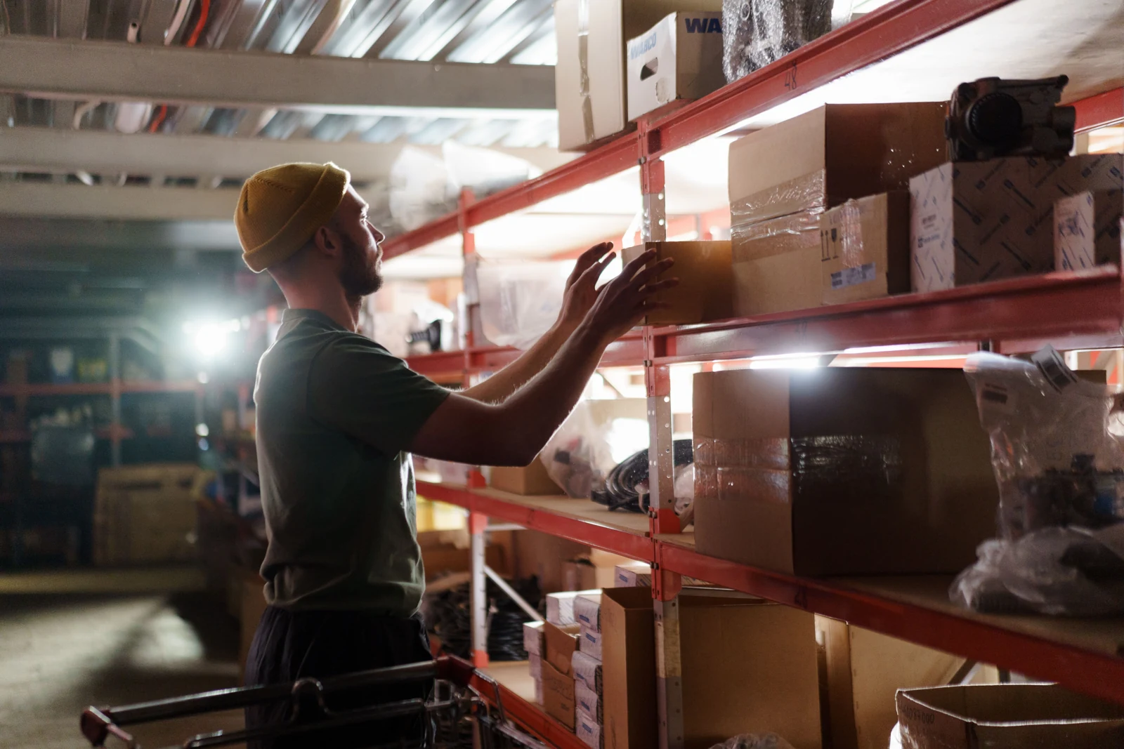 A person handling a cardboard carton on warehouse shelving