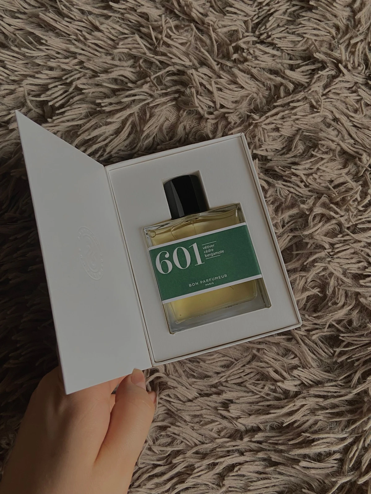 A perfume bottle held within a white insert inside an open presentation box