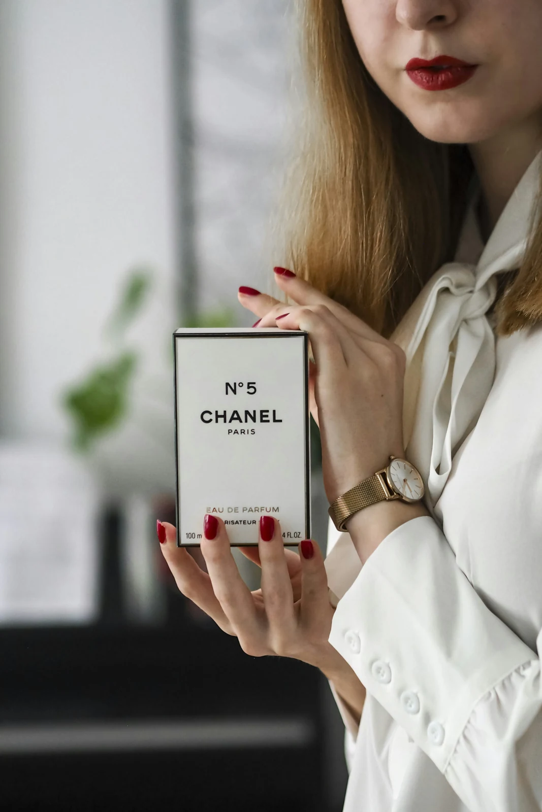 A person holding a branded perfume carton with printed graphics
