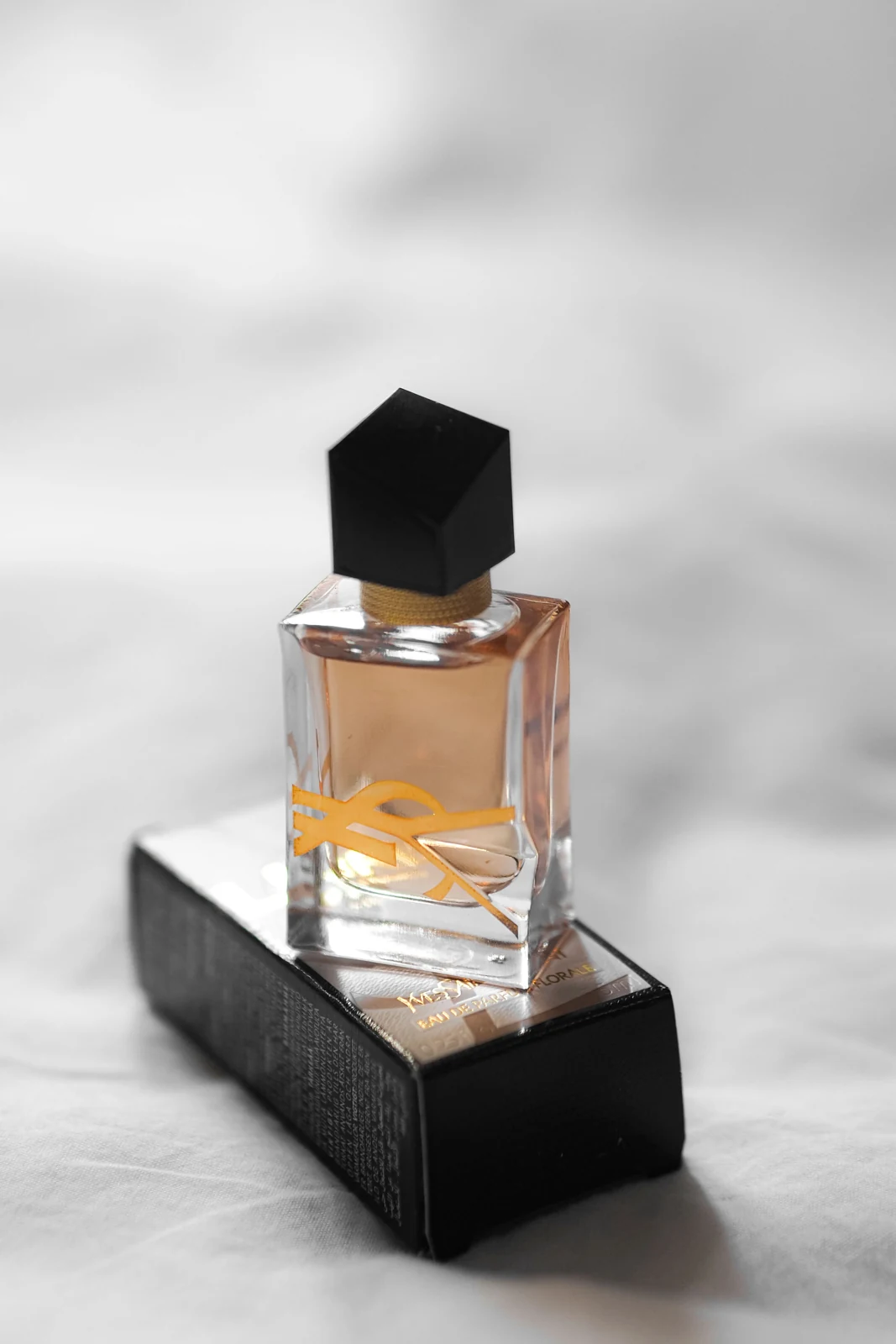 A capped perfume bottle standing on a printed black carton